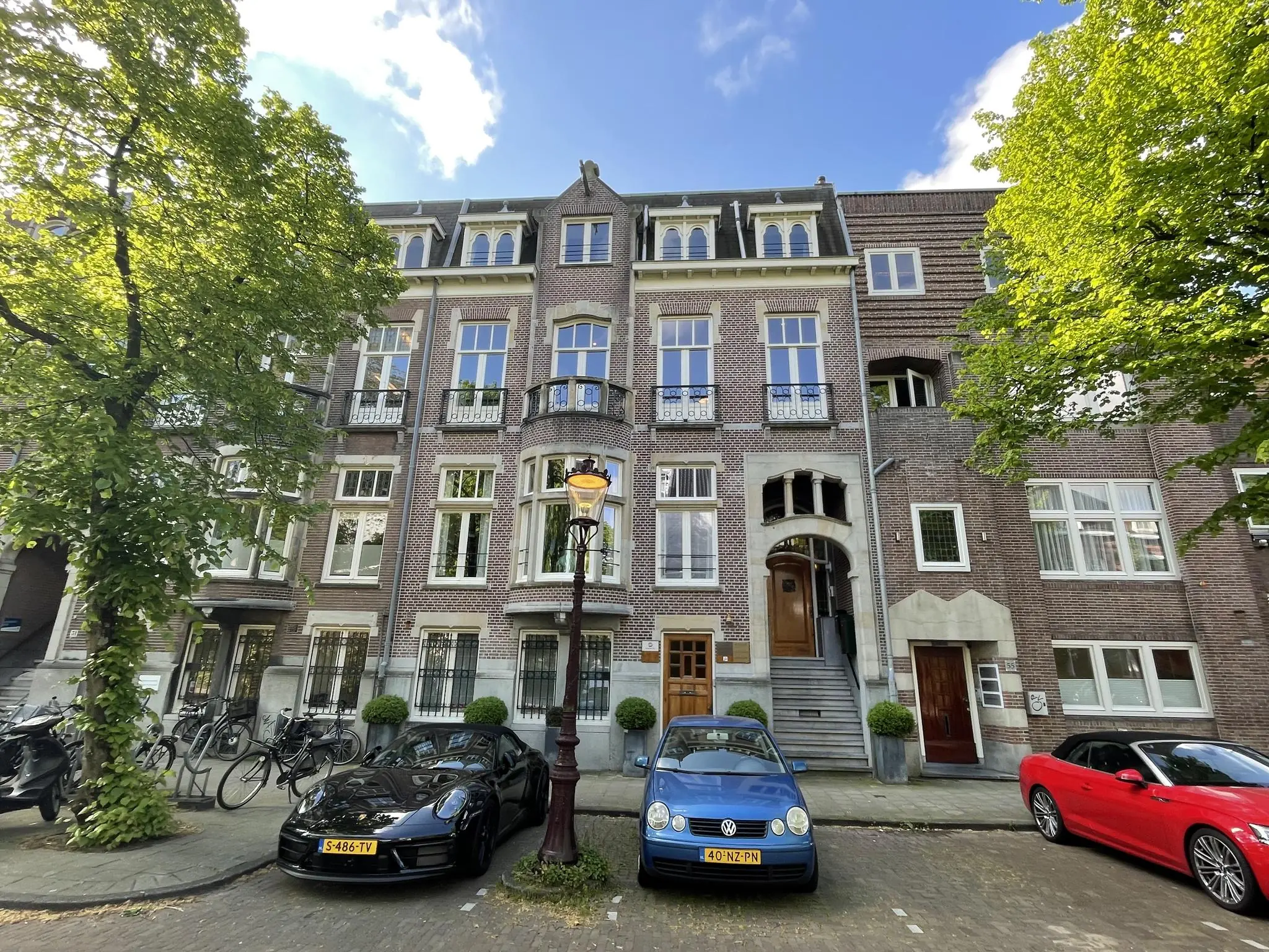 Voorgevel van een statig herenhuis aan de Oranje Nassaulaan met geparkeerde auto’s en bomen langs de straat.